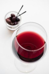 Glass red wine and black olives, close up shallow focus  top view bright surface