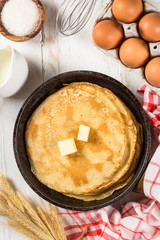 Crepes or thin pancakes in the frying pan with ingredients for cooking.