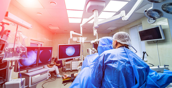 Hospital Interior With Operating Surgery Table, Lamps And Ultra Modern Devices, Technology In Modern Clinic. Medical Results On The Screen. Selective Focus