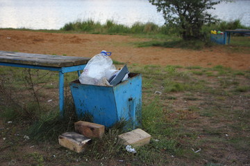 Overloaded trash container with plastic on lake beach on a Sunny summer day, garbage dump in public...