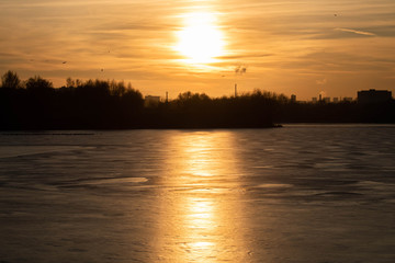 Winter sunset on the background of a frozen pond, lake. Moscow. Russia.