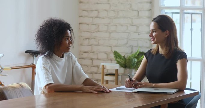 Young female hr manager holding job interview with african applicant.