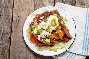 Mexican red enchiladas with potato and pork chorizo also called Potosinas on wooden background