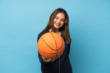 Young brunette girl over isolated blue background with ball of basketball