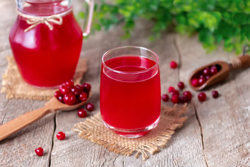 Traditional Russian drink Cranberry mors. Glass of homemade cold cranberry juice with fresh berries on wooden background. Selective focus.