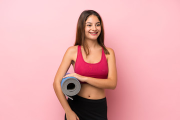 Young sport girl over isolated pink background with a mat and smiling