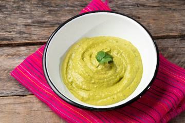 Mexican creamy green sauce with jalapeno pepper on wooden backgrond