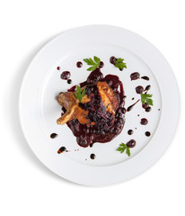 A dish of roasted meat on a bone in berry sauce on a white plate