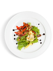 Salad with fresh vegetables and lettuce leaves on a white plate