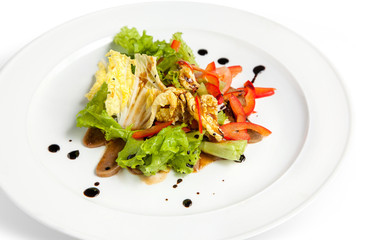 Salad with fresh vegetables and lettuce leaves on a white plate