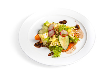 Salad with fresh vegetables and lettuce leaves with red fish on a white plate