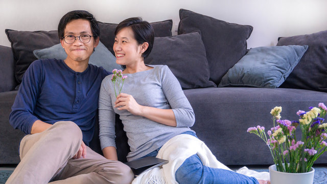 Young asian couple hugging in love at front of sofa in home on valentines day and copy space, use for couple in love content.