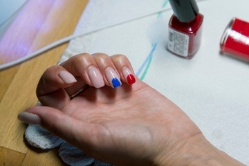 Female hand with beige blue and red varnish. The concept of choosing nail polish