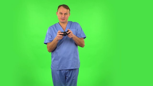 Medical man playing a video game using a wireless controller and loses. Green screen