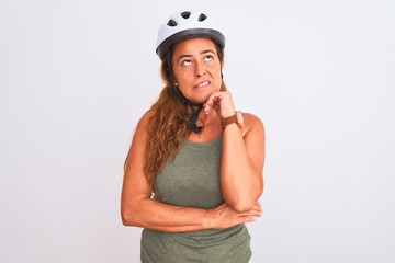 Middle age mature cyclist woman wearing safety helmet over isolated background Thinking worried about a question, concerned and nervous with hand on chin
