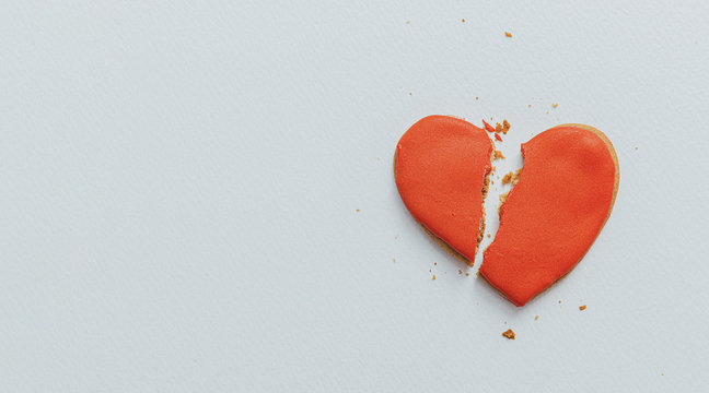 sponge cake with red cream in the shape of a heart broken in half. concept of broken heart and relationship problems..