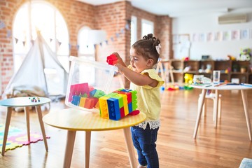 Beautiful toddler playing on the table with building blocks toys at kindergarten