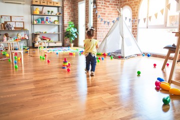 Obraz premium Beautiful toddler playing with striped straws standing at kindergarten