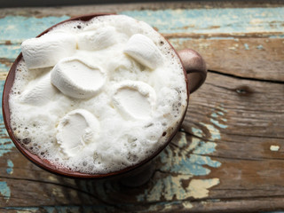 Cappuccino with marshmallows in a cup on an old wooden background. New Year's still life