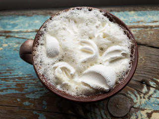 Cappuccino with marshmallows in a cup on an old wooden background. New Year's still life