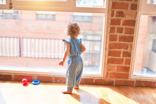 Beautiful caucasian infant playing with toys at colorful playroom. Happy and playful at kindergarten.