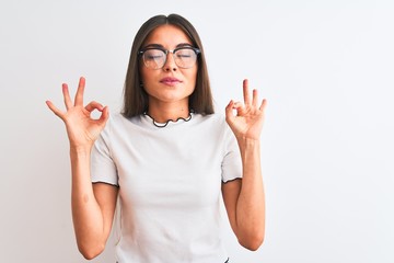 Young beautiful woman wearing casual t-shirt and glasses over isolated white background relax and smiling with eyes closed doing meditation gesture with fingers. Yoga concept.