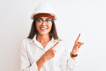 Young beautiful architect woman wearing helmet and glasses over isolated white background smiling...