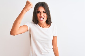 Young beautiful woman wearing casual t-shirt standing over isolated white background angry and mad raising fist frustrated and furious while shouting with anger. Rage and aggressive concept.