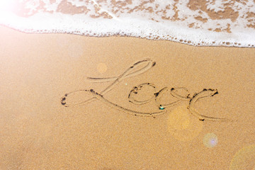 Yellow sand on Mediterranean sea shore with foamy wave and written word 