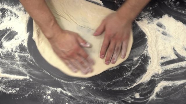 Time lapse making pizza. Men's hands roll out the pepperoni dough, spread the sauce, sprinkle the cheese and put slices of salami