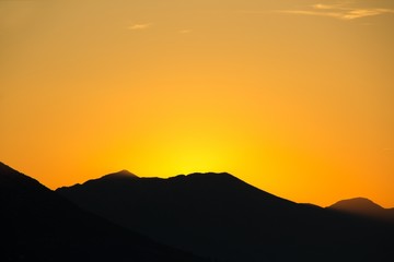 Sunset over the mountains. Golden hour. A silhouette of mountains and a golden sky lit by the last rays of the sun.