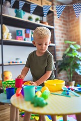 Young caucasian kid playing at kindergarten with toys. Preschooler boy happy at playroom.