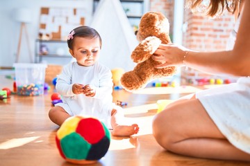 Beautiful infant happy at kindergarten around colorful toys