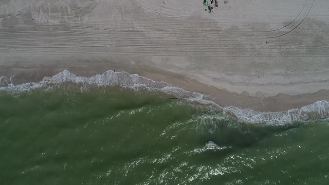 Bird's-eye view of the wild coastline with tires tracks and surf waves