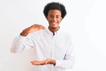 Young african american man wearing elegant shirt standing over isolated white background gesturing with hands showing big and large size sign, measure symbol. Smiling looking at the camera. Measuring