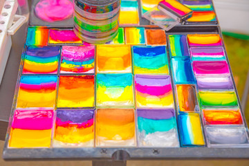 Color paints in the palette of the artist's face art on the street at the festival.