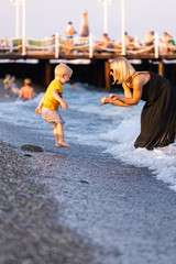 Mother and son having fun on the beach at sunset