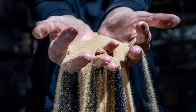 Fine sand trickles through a woman's hands. The sand symbolizes the passing of time.