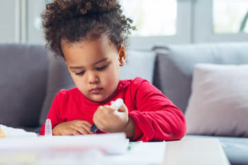 African American little girl drawing with colored pencils.