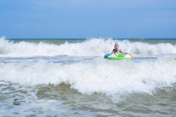 Sea with waves and a girl in an inflatable circle far from the shore. Activities on the beach.