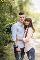Obraz premium Young romantic couple is having fun in summer sunny day in park. Enjoying spending time together in holiday. Man and woman are hugging and smiling.