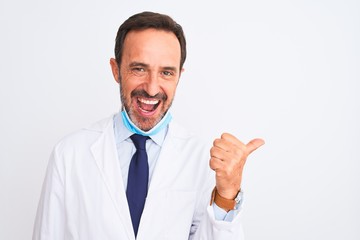 Middle age scientist man wearing coat and medical mask over isolated white background smiling with happy face looking and pointing to the side with thumb up.