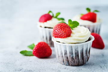 Chocolate cupcakes with cream cheese frosting, mint leaves and strawberries