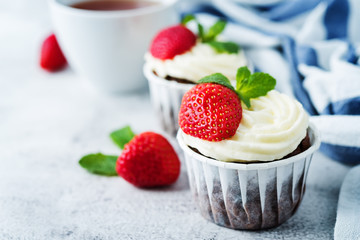 Chocolate cupcakes with cream cheese frosting, mint leaves and strawberries