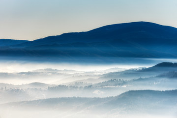 Fototapeta na wymiar Silhouettes of morning winter mountains in the mist
