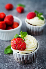 Chocolate cupcakes with cream cheese frosting, mint leaves and strawberries
