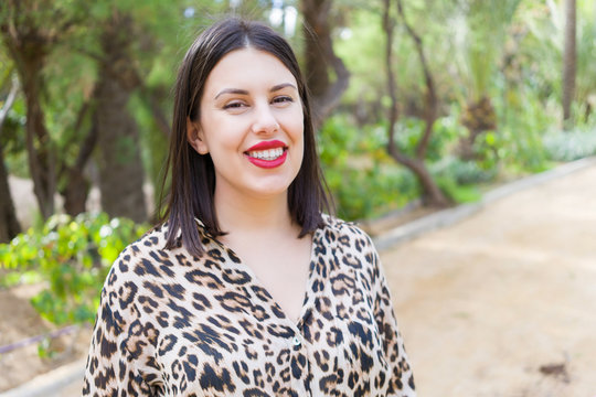 Young beautiful woman with red lips smiling happy at garden