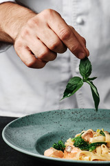 Chef adding basil to pasta