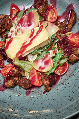Warm salad with beef, brie cheese, radish, tomato and cranberry sauce