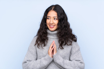 Spanish Chinese woman over isolated blue background scheming something